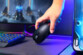 Main nue inclinant la souris gaming sans fil sur un pad de souris dans une configuration multicolore moderne
