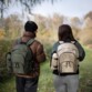 Couple homme-femme en balade dans la nature avec sur leur dos un sac de pique-nique coloris vert pour l'homme et crème pour la femme