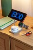 Mise en situation du chargement d'un smartphone à l'horizontale, d'écouteurs sans fil dans leur boîtier et d'une montre connectée sur les trois surfaces de charge à induction Qi compatibles MagSafe magnétiques de la station posée sur un meuble en bois