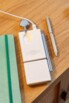 Vue du dessus de l'arrière de la station de chargement 3 en 1 XtremeMac avec surface de chargement pour montre bracelet rabattue, câble USB-C branché à côté d'un carnet de notes et d'un stylo
