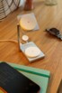 Chargeur sans fil à induction déplié alimenté par câble USB-C sur un meuble en bois à côté de fournitures de bureau, d'une smartwatch éteinte et d'un téléphone portable éteint