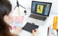 Femme assise à un bureau utilisant la tablette graphique Wacom connectée à un PC portable pour création d'un dessin