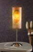 Luminaire photo personnalisé avec une photo de bébé éclairé par une lumière jaune chaleureuse, lampe posée sur une petite table devant un mur noir, raccordée à l'alimentation par un câble avec interrupteur pratique