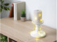 Guirlande LED blanc chaud installée autour d'une bougie et de son bougeoir blanc sculpté sur un meuble en bois contemporain