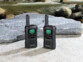 Paire de talkies-walkies avec écran vert allumé placée sur des rochers en extérieur
