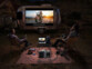 Deux personnes assises sur leur chaise respective devant un écran de cinéma diffusant un film déployé sur une caravane grise en extérieur avec projecteur et cafetière alimentés par la batterie nomade