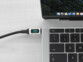 Câble USB-C vers USB-C avec écran LED intégré branché au port USB-C d'un MacBook portable ouvert à l'écran allumé