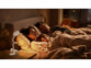 Lampe de lecture CCT rechargeable mise en situation sur un chevet avec une famille qui dort dans un lit