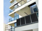 4 panneaux solaires 150 W suspendus au garde-corps d'un balcon d'un immeuble moderne par le biais de leur crochet de suspension