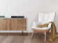 Mise en situation du tuner hi-fi IRS-715 VR-Radio sur un meuble blanc et en bois clair dans un salon, à côté d'un fauteuil beige et blanc sur lequel se trouve une couverture brune