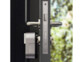 Mécanisme de serrure de porte motorisé et connecté coloris gris métal installé sur une porte d'entrée ouverte sur l'extérieur