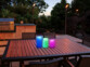 3 bougies LED RVB télécommandées avec luminosité variable et minuterie mises en situation sur une table de jardin