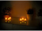 Mise en situation des 6  bougies chauffe plat à LED par Britesta sur un meuble foncé, avec lumière de la pièce éteinte et LED des bougies allumées, bougies placées en 2 groupes de 3 sur le mobilier