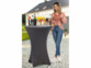Mise en situation de la housse anthracite sur une table de bar haute en extérieur avec boissons posées dessus et femme en jean se servant un verre
