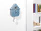 Mise en situation du mécanisme à pendule dans une horloge coucou en bois bleu fixée à un mur blanc à côté d'une bibliothèque de la même couleur