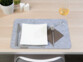 Couteau, fourchette, serviettes en papier et verre posé sur un des 12 dessous-de-table posé lui-même sur une table en bois