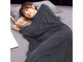 Jeune femme asiatique emmitouflée dans la couverture grise Wilson & Gabor et endormie allongée sur un lit et un coussin de la même couleur