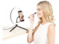 Jeune femme blonde en débardeur blanc se maquillant au pinceau devant la caméra d'un téléphone portable posé sur le support de l'anneau lumineux sur trépied