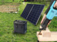 Utilisation du pack batterie avec panneau solaire et câble en extérieur entrain d'alimenter un scie électrique bleue tenue en main par une personne coupant une poutre en bois