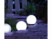 3 sphères brillant dans l'obscurité le long d'un chemin pavé extérieur menant à un portail en bois blanc
