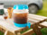 Cubi rempli d'une boisson fraîche type Ice Tea avec glaçons, posé sur une table de pique-nique