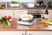 Plaque de cuisson mise en situation sur une table avec des aliments et une casserole sur sa surface vitrocéramique