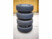 4 pneus de jantes alignés et rangés de manière ordonné sur le support de stockage automobile HP Autozubehör dans un garage avec sol en béton et mur en lambris de bois clair
