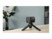 Micro caméra de sécurité noir posée sur une table beige par le biais d'un trépied à trois pieds de support, contrastant avec un mur gris et une plante verte situés au second plan